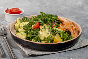 Salad with cucumbers and arugula, shrimp and cherry tomatoes in a light sauce.