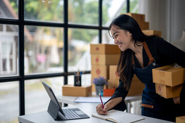 A woman is sitting at a desk with a laptop and a notebook