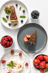 Plates with desserts close-up on a white background. Copy space. Pecan pie, meringue roll and chocolate cake are decorated with berries and mint leaves. Breakfast and tea