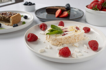 Plates with desserts close-up on a white background. Copy space. Pecan pie, meringue roll and chocolate cake are decorated with berries and mint leaves. Breakfast and tea