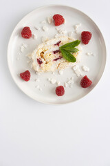 Raspberry meringue roll on a white plate close-up. Dessert on a white background. Breakfast decorated with berries