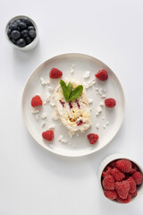 Raspberry meringue roll on a white plate close-up. Dessert on a white background. Breakfast decorated with berries