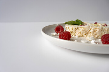 Raspberry meringue roll on a white plate close-up. Dessert on a white background. Breakfast decorated with berries