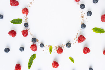 Berries and grated chocolate are laid out in the shape of a circle on a white background. Close-up, top view. Copy space. Pattern. Raspberries, blueberries and mint leaves for decoration