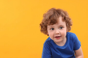Portrait of cute little boy on yellow background, space for text