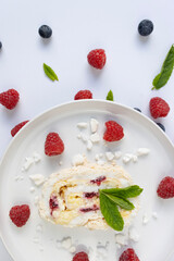 Raspberry meringue roll on a white plate close-up. Dessert on a white background. Breakfast decorated with berries