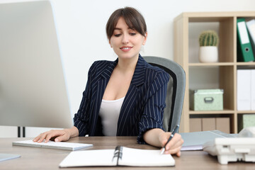 Smiling secretary working at table in office