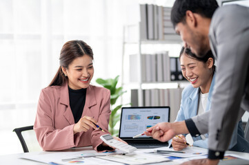 Three people are sitting at a table with a laptop and a calculator