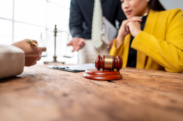 A woman in a yellow jacket sits at a table with a gavel on it
