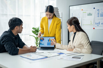 A woman in a yellow jacket is standing in front of a laptop