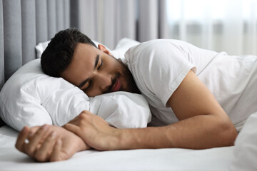Handsome man sleeping on bed at morning