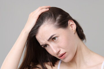 Fototapeta premium Sad woman with hair loss problem on grey background