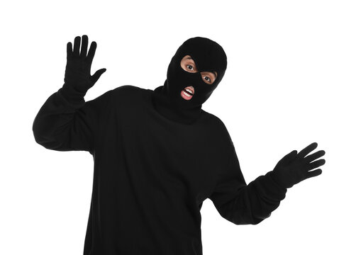 Emotional thief in balaclava raising hands on white background