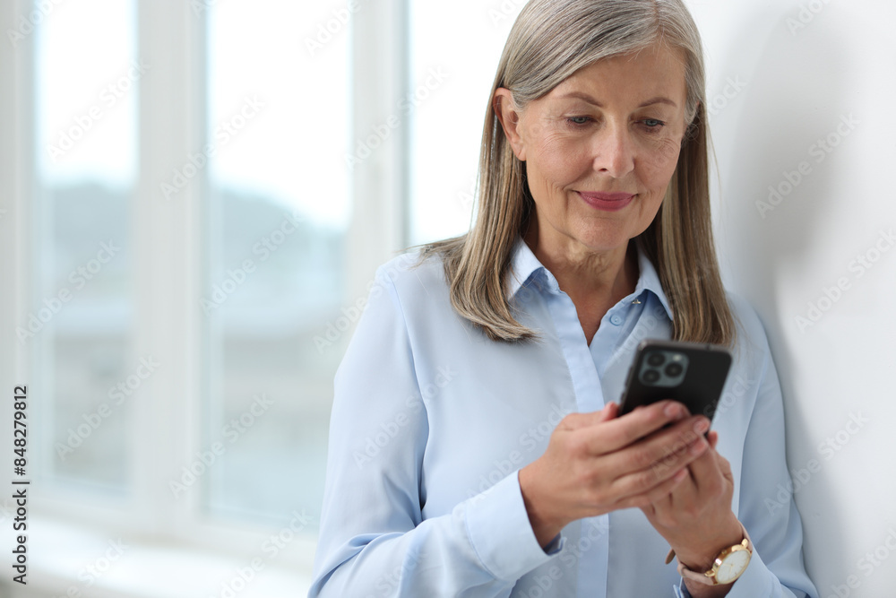 Wall mural senior woman using mobile phone at home, space for text