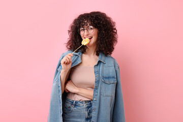 Beautiful woman with lollipop on pink background