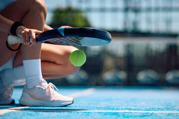 Close up of female paddle tennis player practicing on outdoor court.