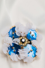 Handmade blue mother-of-pearl brooch on a white cloth, close-up