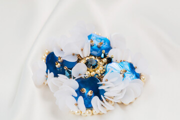 blue mother-of-pearl brooch on a white cloth, close-up