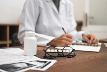 close-up doctor workspace with jar of pills, ultrasound test results, and medical documents, a pharmacist 