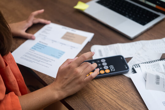 woman at home pores over bank statements and utility bills, embodying financial planning and savings.