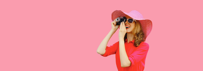 Portrait happy smiling young woman photographer with film camera in summer hat on pink background