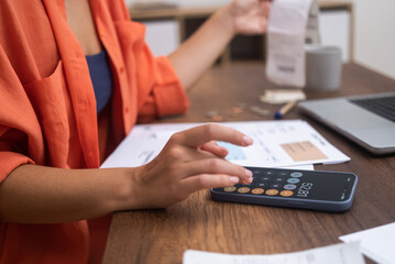 Budget Control: At her desk, alongside a laptop, a woman manages household finances using her...