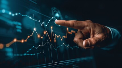 Close-up of a person's hand pointing at a digital financial graph on a screen, highlighting stock market data and analytics in a dark setting.