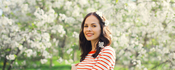Lovely happy smiling young woman in spring blooming garden with white flowers on the trees in park