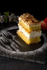 Norwegian cake. With meringue, whipped cream and almonds. Dark background.