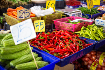 Asian vegetable market. Piles of hot chili peppers and other vegetables with price tags on the counter.
