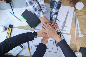 group of businessmen and investors join hands to symbolize cooperation in investing in real estate...