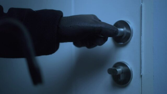 Close-up of the house's door unlocked by a male robber wearing black gloves, home security to prevent the crimination, criminal impact on economic society.
