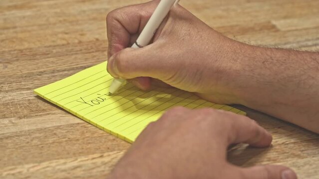 Hand writing "You're Fired" Note pad, lay-off job loss, unemployment, disciplinary action, HR Human resources, 4K