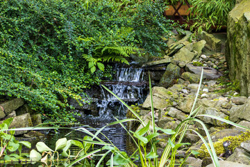 Water flowing over a rocky raft. A small water raft in a zen garden. Decoration, float, water, river. Nature, zen garden, stones, plants.