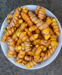 Fresh turmeric roots in a ceramic bowl
