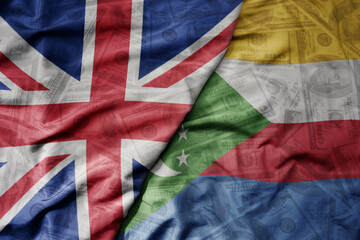 big waving colorful flag of comoros and national flag of great britain on the dollar money background. finance concept.