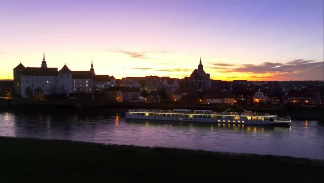slow movement along river elbe in torgau at sunset. old town in the background. cruise ship at the pier.