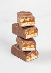 Energy bar. Nougat, caramel with peanuts, in milk chocolate. In the context. White background. Close-up