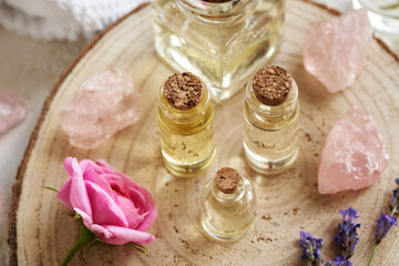 Bottles of aromatherapy essential oil with rose de Mai and lavender flowers and rose quartz gem stones