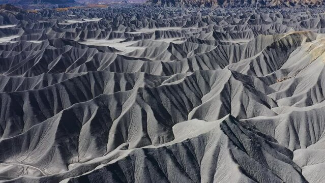 Blue mudstone formations, smooth sharp hills deep gullies of canyon in lifeless and arid desert prairie in western Utah, Usa. Factory butte and moonscape in nature landscape. Aerial view flying