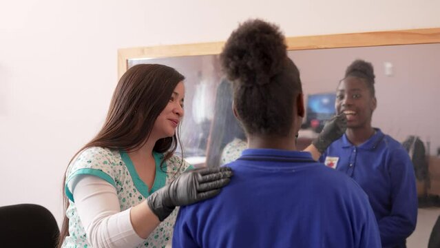 female speech pathologist performing oral evaluation of a teenage black high school student in front of a mirror  inside a school office