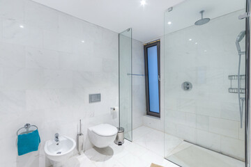 The white tiled bathroom of the hotel, with a window and a spacious shower cabin..
