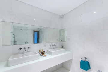 A white hotel bathroom with a panoramic mirror over two sinks