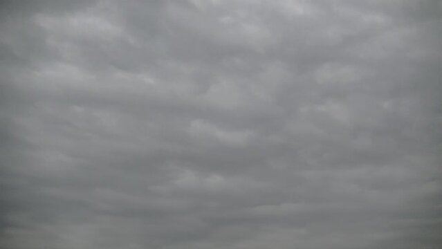 Gray natural background of overcast sky with gray clouds moving quickly - timelapse. Topics: weather, meteorology, climate, wind, space