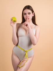 Female model holding apple wrapped with measuring tape. Weight loss concept. Dieting and exercise. Woman measuring her waistline. Fit Girl measuring waist. Sport model measuring waistline.
