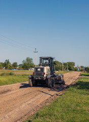 Fototapeta premium a motor grader levels the surface of a rural road, a road machine at road construction