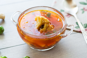 vegetable soup with Brussels sprouts and cauliflower, in a glass plate on a wooden table