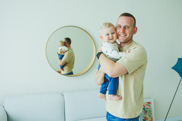 Young smiling dad is playing with his newborn son. Dad and little son.
