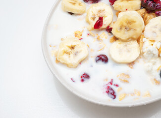 Top view, Bananas with blueberries, cottage cheese and raisins in a plate in the kitchen. With milk muesli with cottage cheese and cherry and black berry fruits