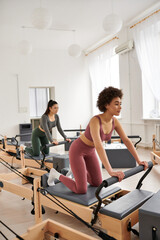 Young women in gym, exercising on stationary machine with focused determination.